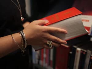 En person med samiske smykker holder Norges lover i hånden